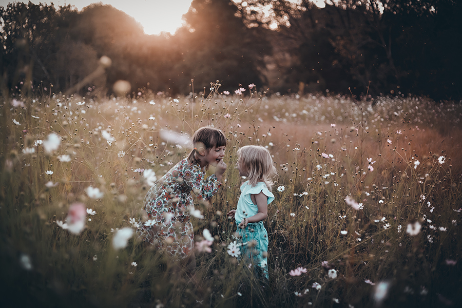 big girl showing her missing teeth to little girl